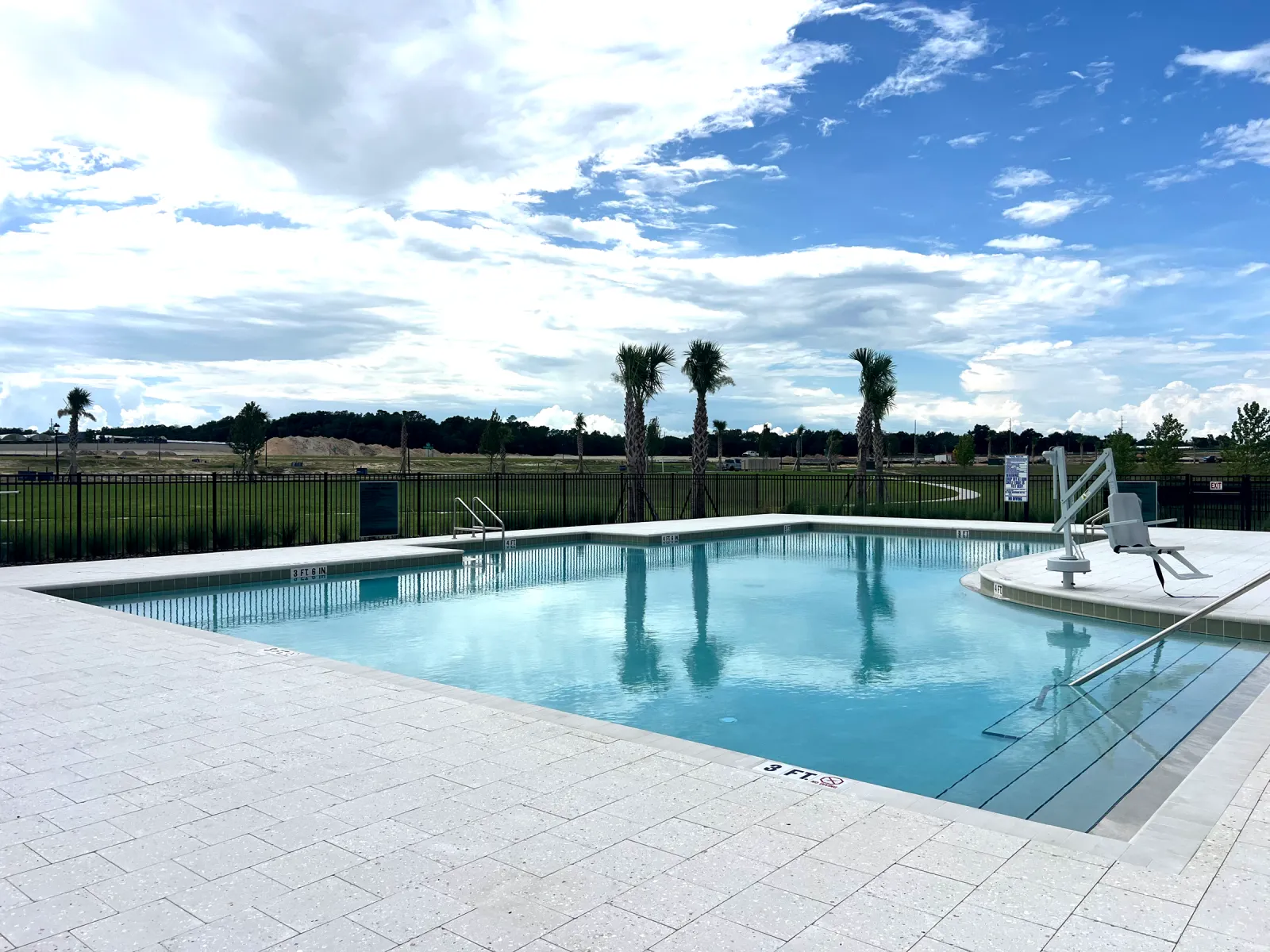 Large community amenity pool with lap lanes, depth markers, and an ADA pool lift, built by Next Level Pools and Spas in Central Florida