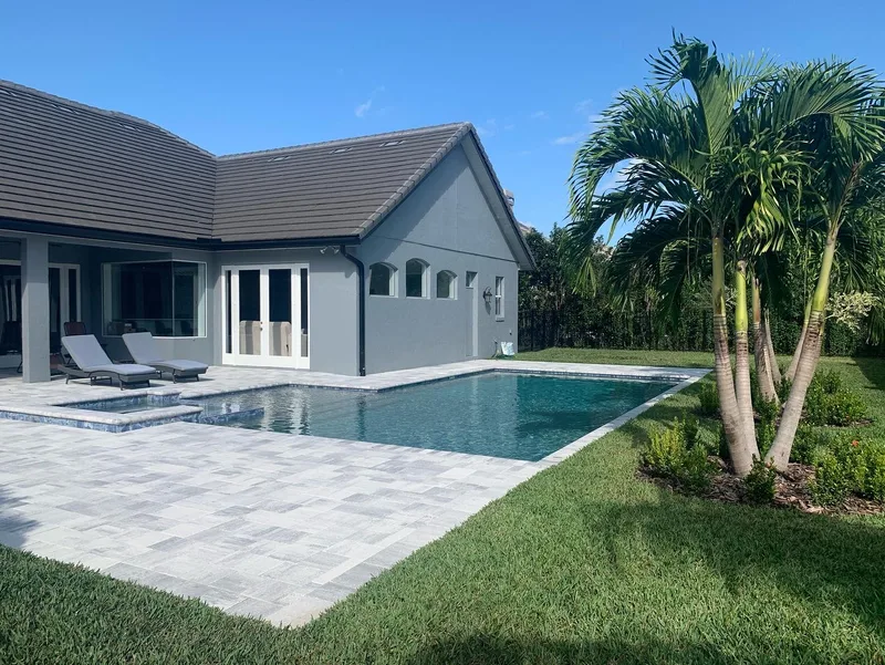 Custom rectangular pool with travertine paver deck and mature palm landscaping — Next Level build in Central Florida