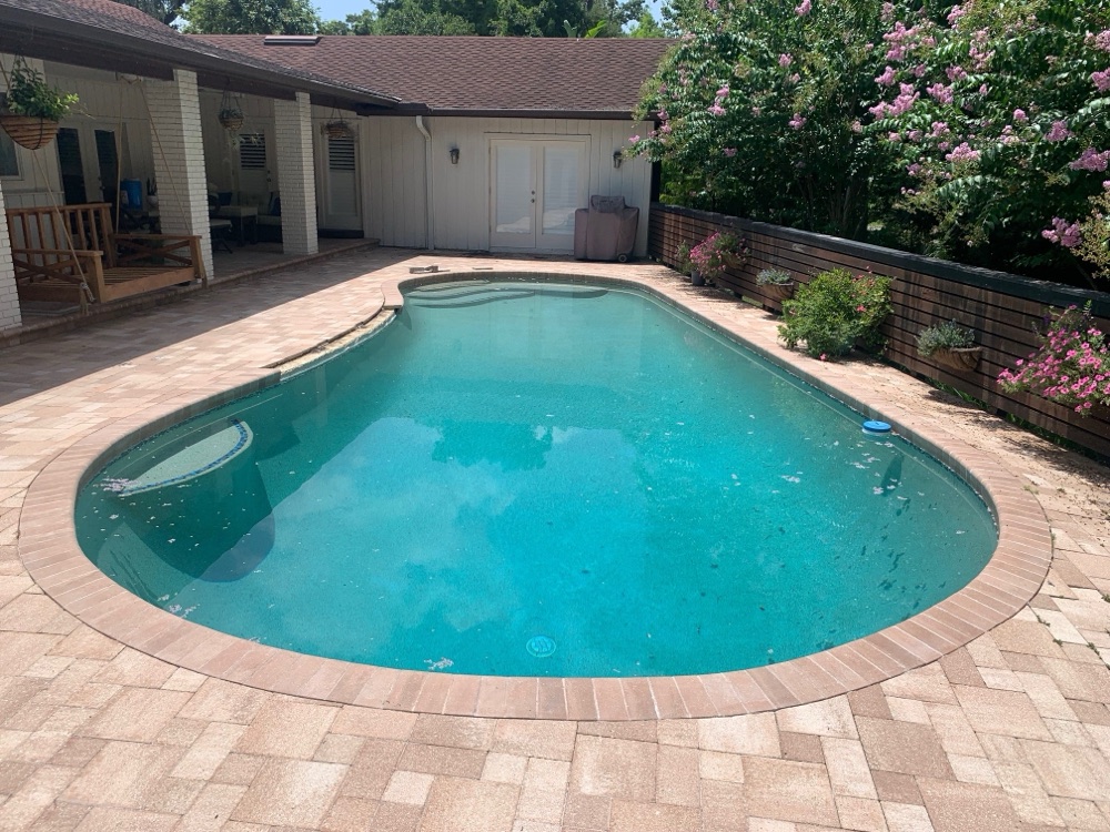 Brick coping to dark resurface + travertine deck — before, view 1