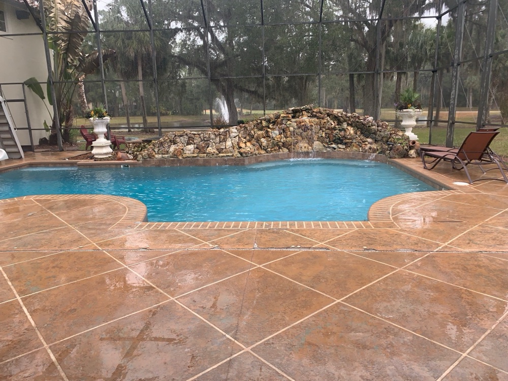 Rock waterfall to pebble sun shelf + loungers — before, view 1