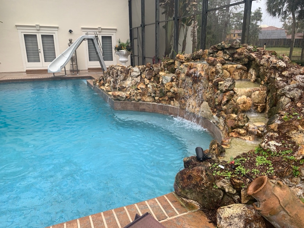 Rock waterfall to pebble sun shelf + loungers — before, view 3