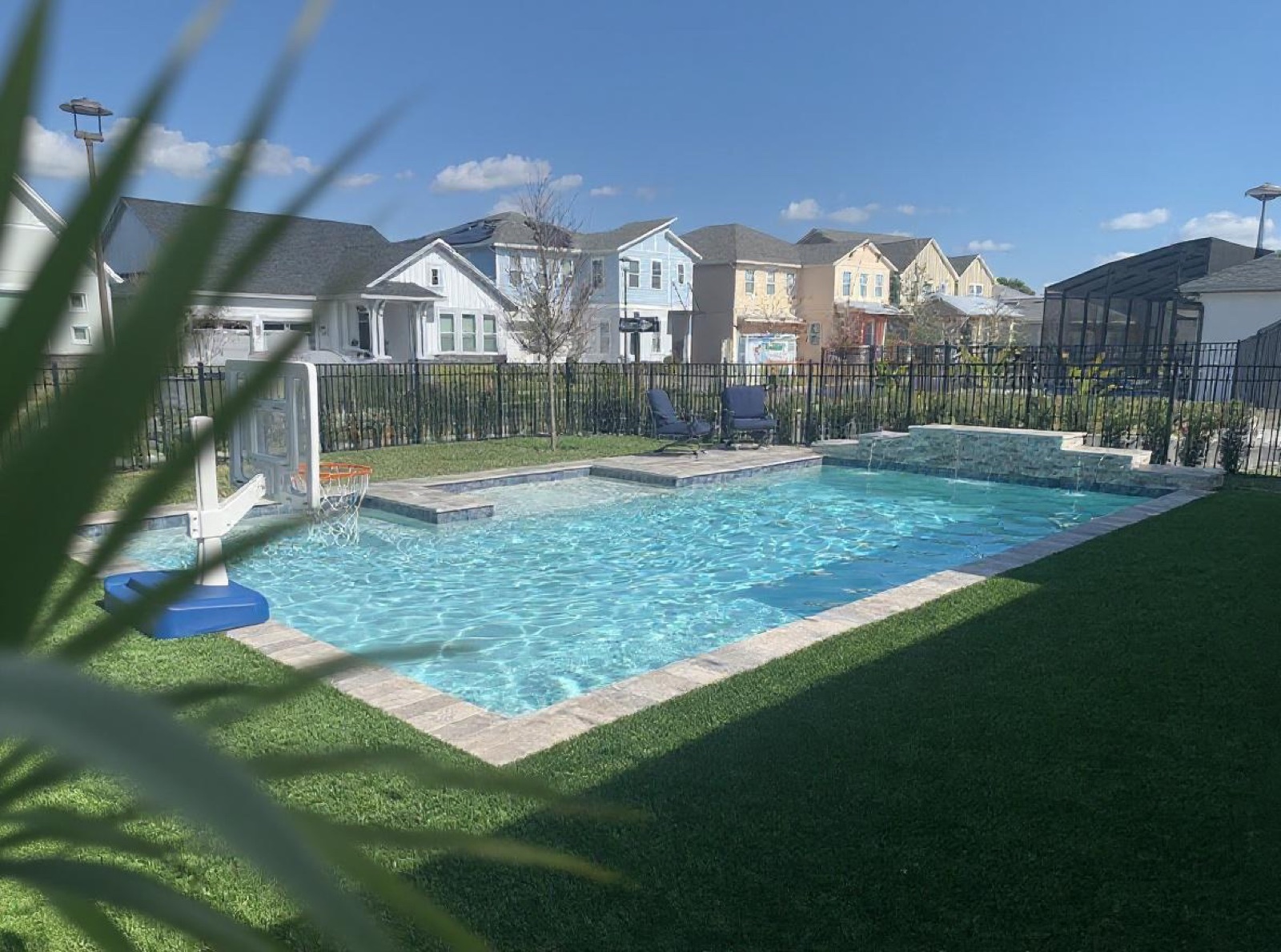 Pool with deep blue water, scupper wall feature, and poolside seating